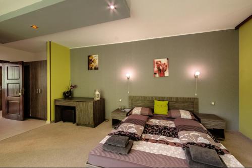 a bedroom with a large bed and a desk at Family Hotel BOHEMA in Ognyanovo