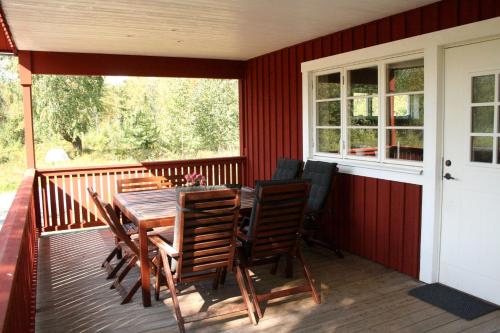 una terraza con mesa de madera y sillas. en Grönelid Gård en Tived