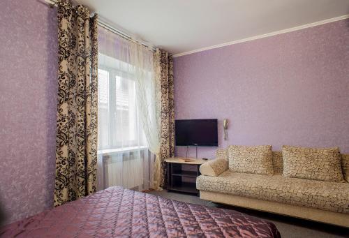 1 dormitorio con cama, sofá y TV en Domik v Samare Hotel, en Samara