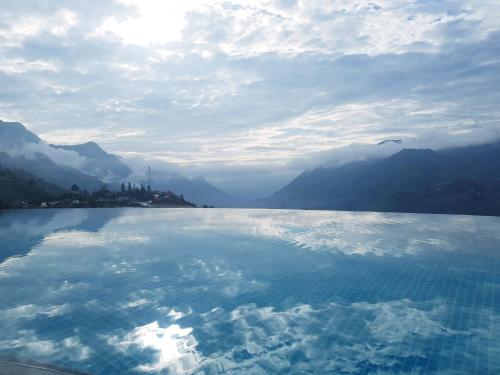 a large pool of water with mountains in the background at Sapa Clay House - Mountain Retreat in Sa Pa