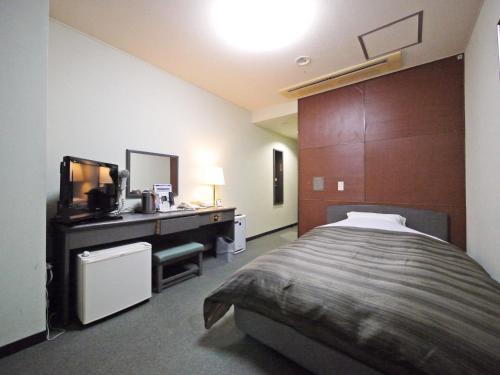 a bedroom with a bed and a vanity and a mirror at Hotel Route-Inn Court Nirasaki in Nirasaki