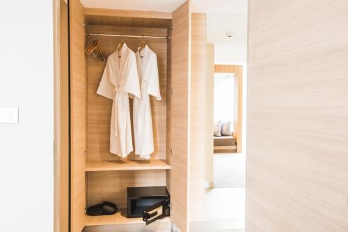 a walk in closet with white clothes and a mirror at twothree a homely hotel - SHA Extra Plus in Bangkok