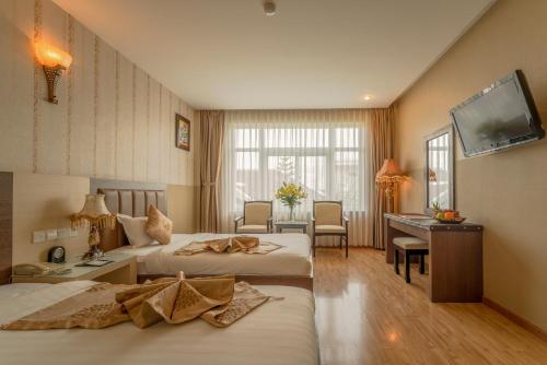 a hotel room with two beds and a desk at Eden Plaza Da Nang Hotel in Da Nang