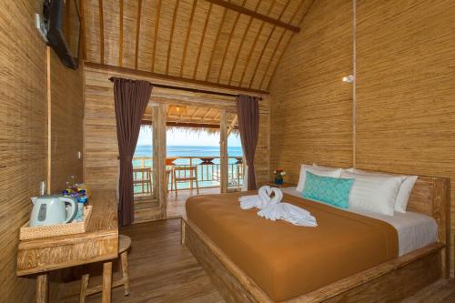 Schlafzimmer mit einem Bett, einem TV und einem Balkon in der Unterkunft The Dewi Sun Sun Suite in Nusa Penida