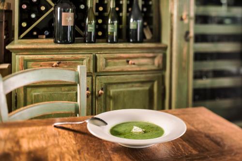 a bowl of green soup on a wooden table at KABAJ Wine & Dine in Dobrovo