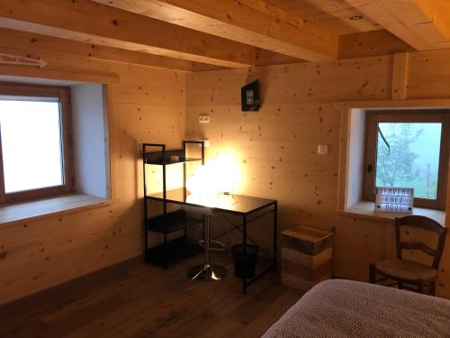 una camera in una baita di tronchi con una scrivania e due finestre di Chalet du bois des Fugiers a Ugine