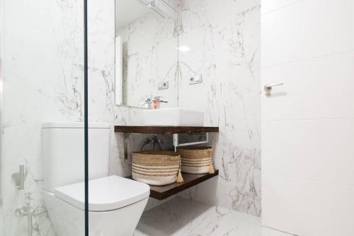 a white bathroom with a toilet and a sink at Apartamento Puertoplaya II in Puerto de Mazarrón
