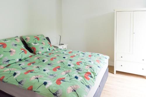 a bed with a green comforter with flowers on it at Ferienwohnung am Wall in Soest