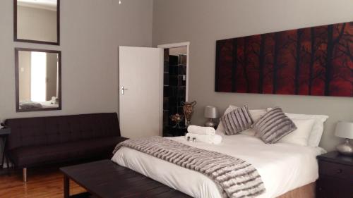 a bedroom with a large bed and a couch at 44 on Ennis Guest Lodge and Restaurant - NO LOAD SHEDDDING in Ermelo