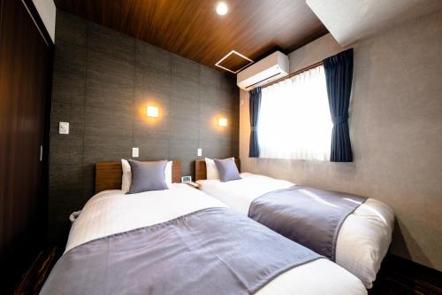 two beds in a small room with a window at 22 ORIYA Mt Fuji -錦NISHIKI- in Fujikawaguchiko