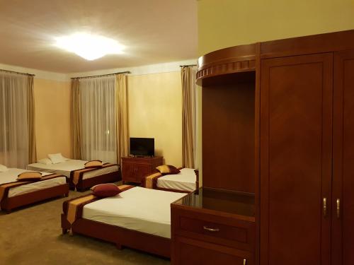 a hotel room with three beds and a tv at Rezydencja Pod Zegarem in Trzebinia