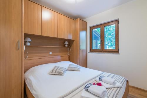 una camera da letto con un grande letto bianco e armadi in legno di Apartments Insula Aurea a Klimno