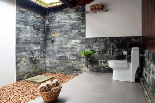 a bathroom with a toilet and a basket of logs at StayVista at La Riva Heritage Villa with Bicycle in Alleppey