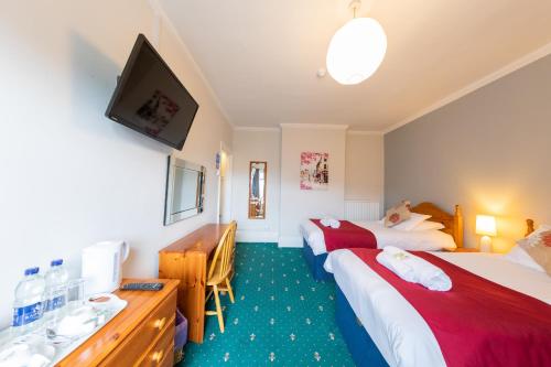 a hotel room with two beds and a flat screen tv at The Clee Hotel - Cleethorpes, Grimsby, Lincolnshire in Cleethorpes