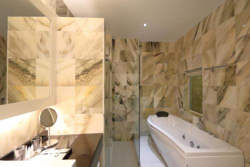 a bathroom with a tub and a sink at The Guest Hotel & Spa in Port Dickson