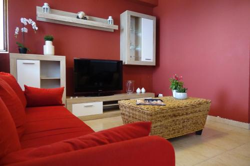 a red living room with a tv and a red wall at Poseidone Sea Apartment Taormina in Mazzeo