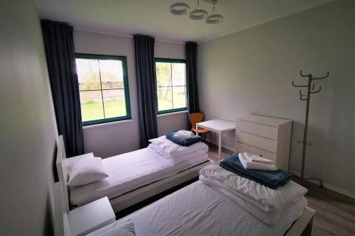 two beds in a room with two windows at Centrum Żeglarskie Domki Kempingowe in Szczecin