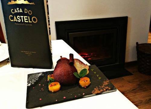 een bord met een granaatappel op een tafel met een boek bij Casa do Castelo Ourém in Ourém