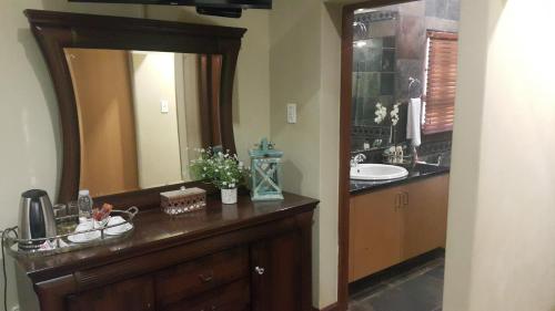 ein Badezimmer mit einem Waschbecken und einem großen Spiegel in der Unterkunft 93 on Celliers Guesthouse in Louis Trichardt