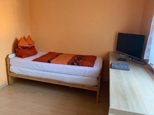 a small bedroom with a bed and a television at Gästezimmer Fuchs in Neuhausen auf den Fildern