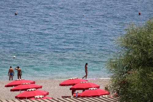 a group of red umbrellas on the beach at Poseidone Sea Apartment Taormina in Mazzeo