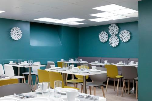une salle à manger avec des tables blanches et des chaises jaunes dans l'établissement Montparnasse Alésia, à Paris