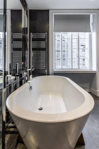 a large white tub in a bathroom with a window at The Inn on the Mile in Edinburgh