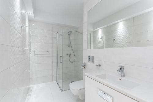 a white bathroom with a shower and a toilet at Król Plaza Spa & Wellness in Jarosławiec