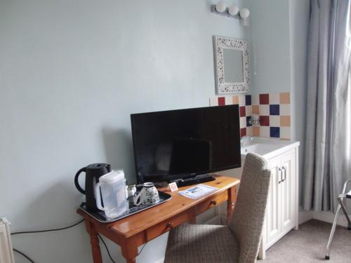 a desk with a computer monitor and a chair at Llanwrtyd Hall B&B Angelis Holistic Retreat in Llanwrtyd Wells