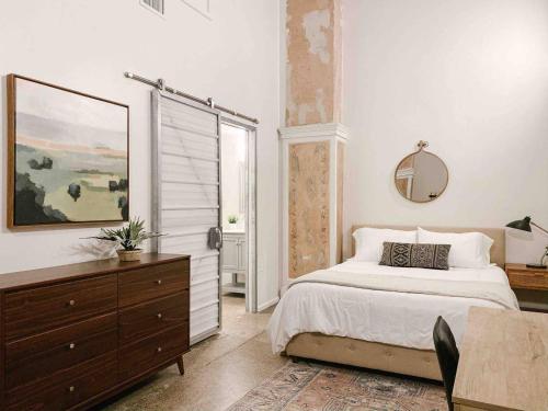 a bedroom with a bed and a dresser and a mirror at Modern Downtown Loft on Gay St in Knoxville