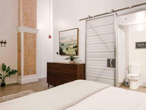 a bedroom with a bed and a wooden dresser at Modern Downtown Loft on Gay St in Knoxville