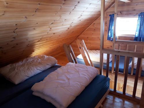 a room with two beds in a log cabin at Dalen Gaard camping og hytter in Geiranger