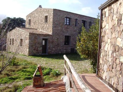 an old stone building with a fence in front of it at Agriturismo Il Muto di Gallura in Aggius