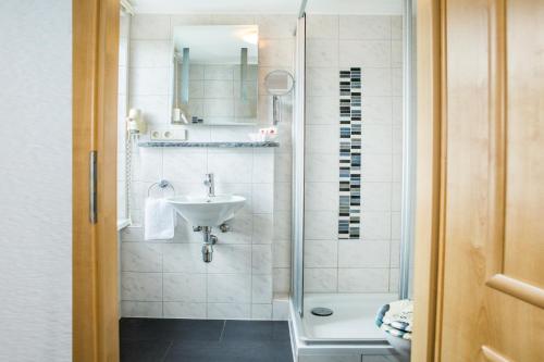 ein Bad mit einem Waschbecken und einer Dusche in der Unterkunft Traditions-Gasthaus Bayrischer Hof in Leutkirch im Allgäu