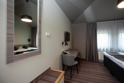 a bedroom with a bed and a desk and a mirror at Hotel Cēsis in Cēsis