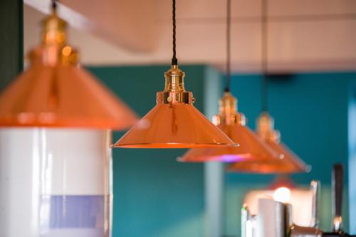 a group of three lights hanging from a ceiling at County Arms in Truro