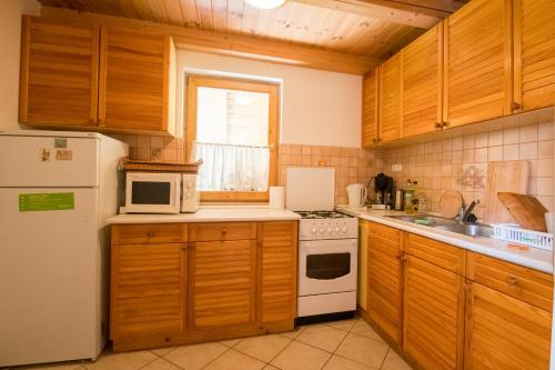 a kitchen with wooden cabinets and a white refrigerator at Ancsa Vendégház in Visegrád