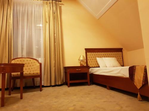 a bedroom with a bed and a chair and a window at Rezydencja Pod Zegarem in Trzebinia
