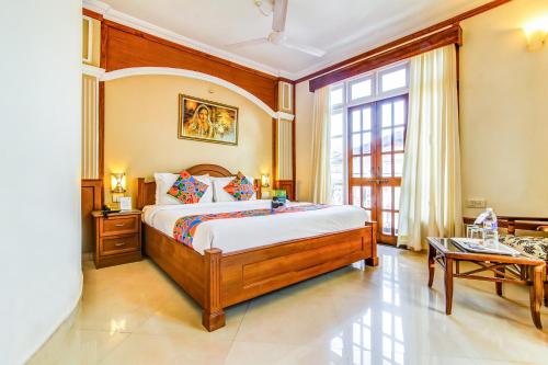 a bedroom with a bed and a large window at Sunset Beach Resort in Candolim