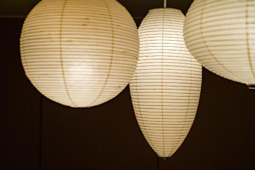 three white paper lanterns hanging on a wall at MATERIAL Fuchomae in Kyoto