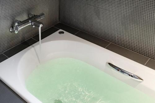 a bath tub filled with water in a bathroom at MATERIAL Fuchomae in Kyoto