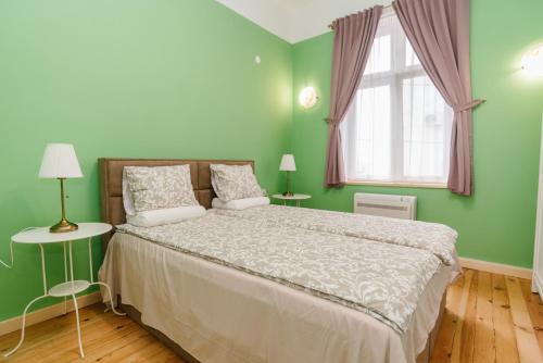 a green bedroom with a bed and a window at Апартамент ELSOR in Burgas City