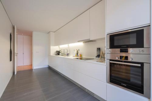 a white kitchen with a microwave and a stove at Kame House - Gym & Sauna next to the Beach in Ponta Delgada