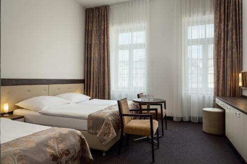 カルロヴィ・ヴァリにあるHotel Maltaのベッド2台とテーブルが備わるホテルルームです。
