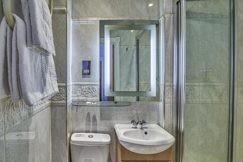 a bathroom with a sink and a toilet and a mirror at Hyde Park Radnor Hotel B&B in London