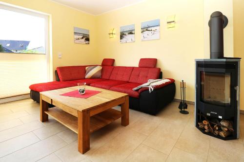 a living room with a red couch and a fireplace at Ferienhaus Sinha_SOMM in Karlshagen