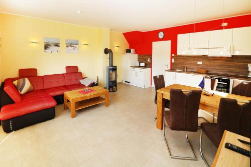 オストゼーバート・カールスハーゲンにあるFerienhaus Sinha_SOMMのリビングルーム(赤いソファ付)、キッチン