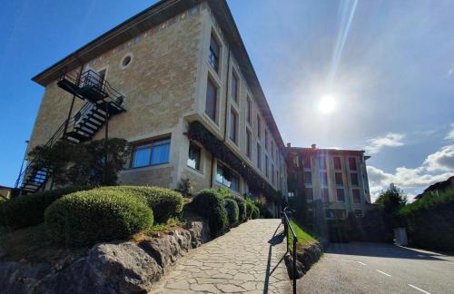 a large brick building with the sun behind it at Los Acebos Arriondas in Arriondas
