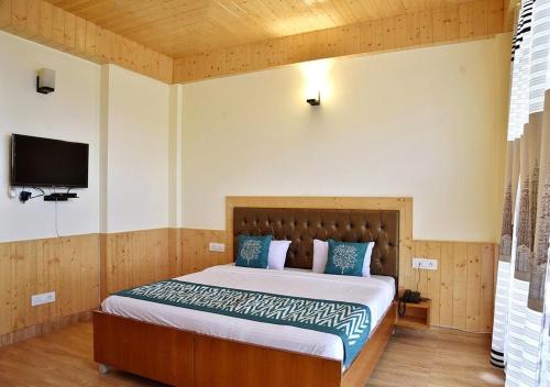 a bedroom with a bed with a tv on the wall at Ditto Room Kufri Ashray in Shimla