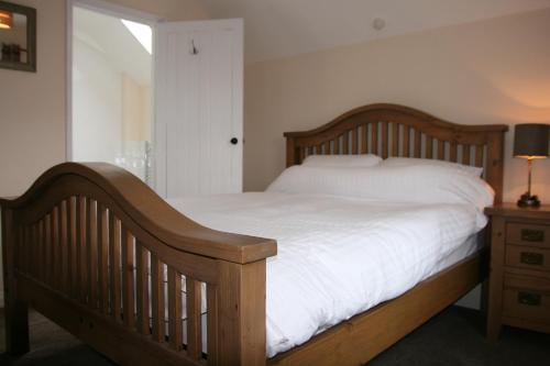 a bedroom with a wooden bed with white sheets and a lamp at Hawthorn in Crayke YO61 4TE in York